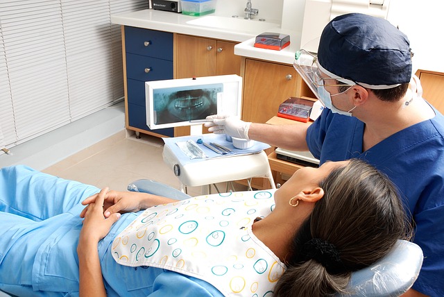 Dentista e paciente analisando exame radiográfico em uma tela.